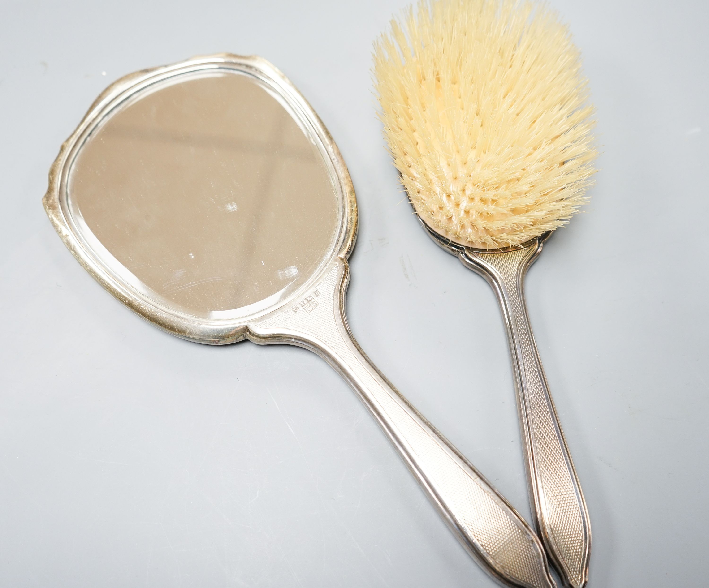 A silver-backed hand mirror and hairbrush, a silver-mounted scent bottle and a powder bowl.